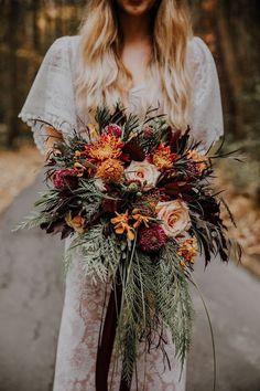 a woman in white dress holding a bouquet with orange and red flowers on it's side