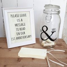 there is a glass jar with a sign on it next to a small white frame