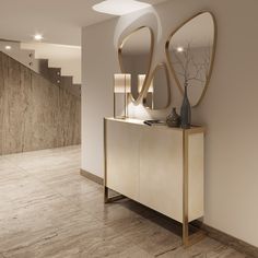 a white and gold console with two mirrors on the wall, next to a staircase