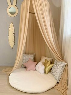 a bed with a canopy and pillows on the floor in front of a wall mounted mirror