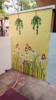 a fire hydrant in front of a wall with flowers painted on it and two hoses connected to it