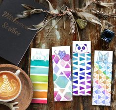 four different colored papers with designs on them next to a cup of coffee