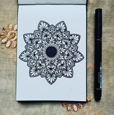 a notepad with a black and white flower design on it next to a pen