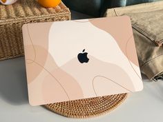 an apple laptop computer sitting on top of a wicker basket next to oranges