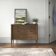 a room with a dresser, rug and painting on the wall