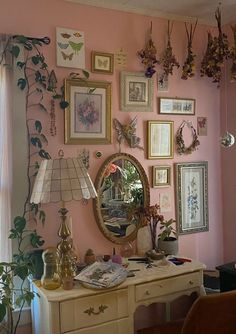 a room with pink walls and lots of pictures on the wall, including a mirror