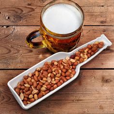 there is a glass of beer and some nuts on the table