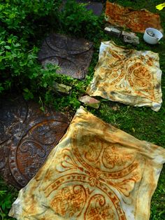 some cloths are laying out on the ground in the grass and one is yellow