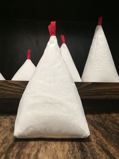 three white cones with red bows on them are sitting in front of a wooden frame