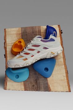 a pair of shoes sitting on top of a piece of wood next to an orange and blue object