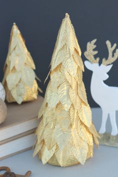 two gold christmas trees sitting on top of a table next to a pair of scissors