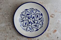 a blue and white plate with fish on it sitting on a counter top next to a tile floor