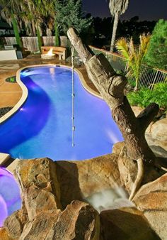 an outdoor swimming pool surrounded by rocks and trees