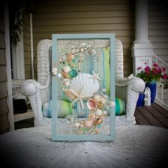 a sea shell frame sitting on top of a table next to two wicker chairs