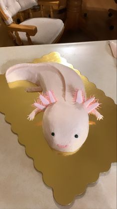 a cake shaped like an animal with pink ears and tail sitting on a gold plate