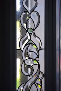 a glass window with spiral designs on the outside and inside, in front of a door