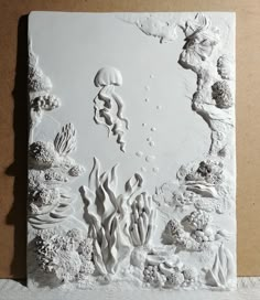 an art work is displayed on the wall in front of a piece of paper that has been cut out to look like corals