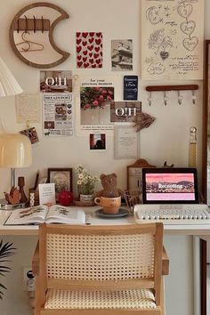 a white desk topped with a laptop computer next to a lamp and pictures on the wall