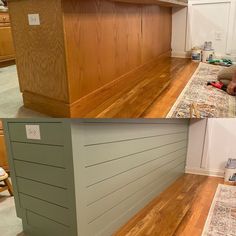 a man laying on the floor in front of a counter top with wood paneling