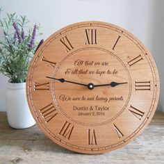 a wooden clock sitting on top of a table next to a vase filled with flowers