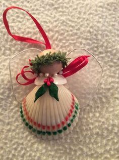 an ornament with a shell and holly wreath on it, sitting on top of a white blanket