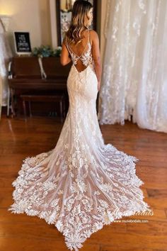 a woman standing in front of a piano wearing a wedding dress with an open back