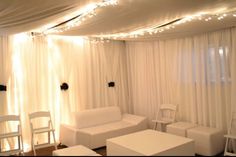 a living room with white furniture and string lights