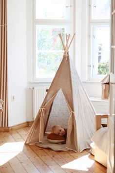 a child's teepeet in the corner of a room with wooden floors