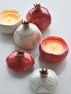 four ceramic apples and two candles on a white surface