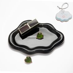 two pieces of jewelry sitting on top of a black plate next to a keychain