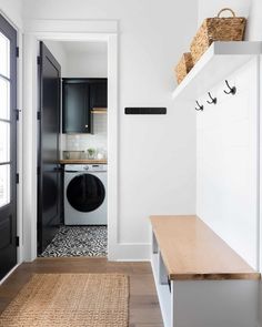 a washer and dryer in a small room next to a door with hooks on it