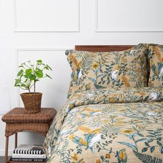 a bed with yellow and blue floral bedspread next to a wicker side table