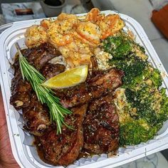 a person holding up a tray of food with shrimp, broccoli and shrimp