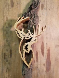 a deer's head carved into the side of a tree branch on a wooden surface