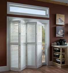 a room with wooden floors and white shutters on the doors that lead to an outside patio