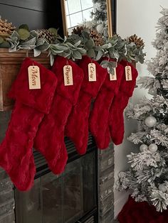 christmas stockings hanging from a mantel decorated with greenery