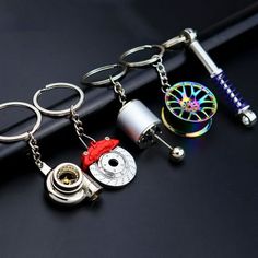 several different types of keychains on top of a black table next to a pen