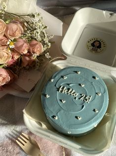 a blue frosted cake sitting on top of a table next to a bouquet of flowers