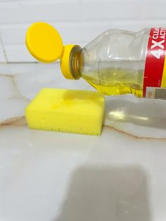 a yellow sponge is next to a bottle of soap on a white tile countertop