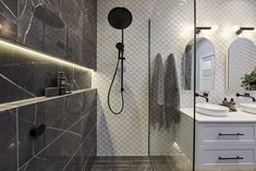 a bathroom with two sinks, mirrors and a shower head in the middle of it