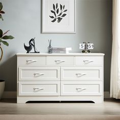 a white dresser sitting in a living room next to a window