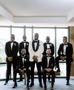 a group of men in tuxedos standing next to each other near a window