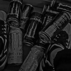 black and white photograph of monster energy drink cans with shoes on the floor next to them