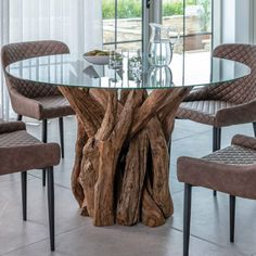 a glass table with chairs around it and a tree trunk in the middle of the table