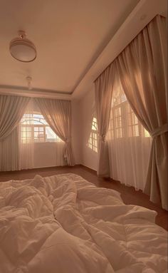 an empty bedroom with white sheets and curtains