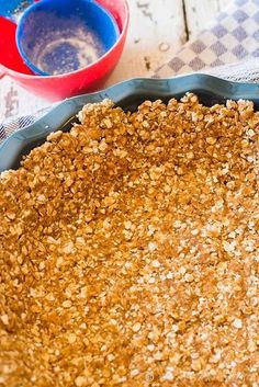 an uncooked pie crust with oats in the middle and two bowls behind it