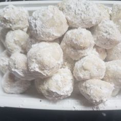 powdered sugar balls in a white dish on a table