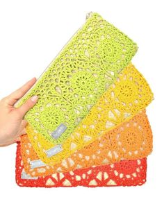 a hand is holding four crocheted placemats on top of each other