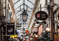 an indoor shopping mall with lots of signs hanging from it's ceiling and lights on either side