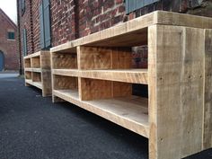 three wooden shelves sitting next to each other in front of a brick building